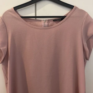 Rosa blus från ONLY med dragkedja i ryggen  - Säljer en gammelrosa blus från ONLY i storlek 36. Blusen har rund halsringning, korta ärmar och en kort dragkedja bak i nacken. Materialet är lätt strukturerat och modellen är lite längre baktill för en snygg siluett.
