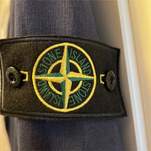 Mörkblå Stone Island sweatshirt - Säljer en mörkblå sweatshirt från Stone Island med den klassiska loggan på vänster ärm. Tröjan har rund halsringning, ribbade muddar och är tillverkad i mjuk bomull. Perfekt för dig som gillar streetwear och vill ha en clean look.