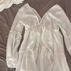 Vit omlottklänning med volanger - Superfin vit klänning med omlott-skärning och v-ringning. Perfekta sommar eller strand klänningen, står att den är one size men är själv en strl s/m och den sitter perfekt så lämplig till alla från strl xs-s💕
