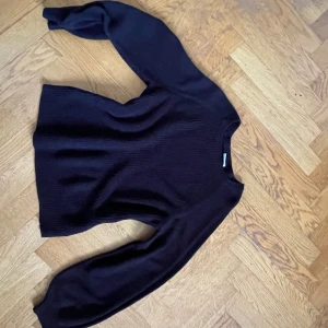 Svart stickad tröja från Vila - Mysig svart stickad tröja från Vila i storlek S. Tröjan har långärmade ballongärmar med breda muddar och ett ribbat mönster över hela plagget. Perfekt för kyliga dagar och enkel att matcha med jeans eller kjol.