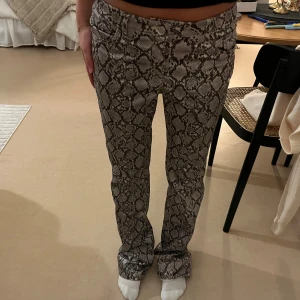 Weekday snakeprint byxor, stl 38 - Snygga byxor från Weekday i storlek 38 med grått och svart ormmönster. Modellen är raka och har normal passform med klassisk midja. Har aldrig använt dem!