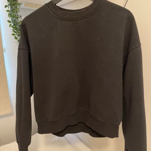Svart croppad sweatshirt - En svart croppad sweatshirt med rund halsringning och långa ärmar. Tröjan har ribbade muddar vid ärmslut och nederkant, samt en avslappnad passform. 