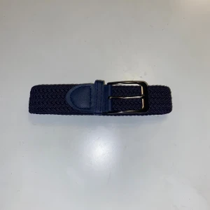 Mörkblått flätat bälte 110cm  -  mörkblått bälte – 110 cm Snyggt och klassiskt mörkblått bälte i fint skick! Bältet är 110 cm långt och 3,5 cm brett, perfekt för jeans. Färgen är tidlös och passar till det mesta – ett perfekt komplement till din garderob. Spännet är i metall och ger en elegant men enkel look.  ✅ Längd: 110 cm ✅ Bredd: 3,5 cm ✅ Färg: Mörkblå ✅ Passar både vardag och fest