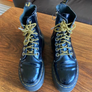 Svarta Platå Dr. Martens  - Säljer ett par svarta Dr. Martens Jadon Max i storlek 38. De är i läder har grov platåsula och gula snören. Skorna har dragkedja tradig spänne på ena skon, därav metallring. Men annars är de hela utöver lite repor.  De kan vara lite små i storleken. Men de är supersköna och snygga. Säljer för 600 kr + frakt (köpare står för frakt 💕