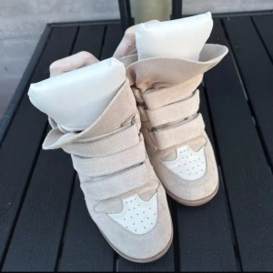 Beige Isabel Marant wedge sneakers - Säljer ett par ikoniska beige wedge sneakers från Isabel Marant i beige med vita detaljer. Storlek 36 passar på 37. De har 5 cm klack. 