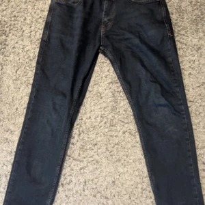 Mörkblå jeansbyxor från Lacoste  - W32 L34 Pris kan diskuteras              Snygga mörkblå jeans från Lacoste med klassisk femficksdesign och raka ben. Jeansen har en normal passform och är tillverkade i ett mjukt denimtyg som sitter skönt hela dagen. Perfekta för dig som gillar stilrena och tidlösa jeans.