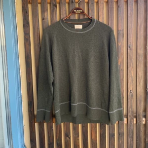 Grön stickad tröja från Nudie  - Grön stickad tröja från Nudie Jeans i storlek M/L. Tunn men varm, vita och orangea sömmar som även är tydligt placerade för att ge snyggare och större avslut i ärmar och midja. 