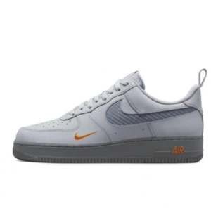 Nike Air Force 1 grå med orange detaljer - Säljer ett par Nike Air Force 1 sneakers i ljusgrått skinn med mörkgrå sula. Skorna har en unik gråmelerad swoosh och små orangea detaljer på sidan och vid AIR-loggan. Klassisk siluett med snörning och perforerad tå för extra ventilation. Jag köpte skorna för 2600kr och jag säljer de för 1400kr.