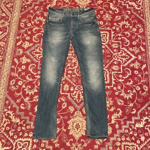  Garcia Jeans  - Snygga blå jeans från Garcia Jeans med klassisk femficksdesign och diskret slitning på låren. Jeansen har rak passform och normal midja, med läderpatch bak i midjan och tydliga sömmar. Perfekta för en avslappnad och stilren look.