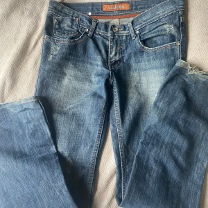 Blå jeans från Remode Inc. - Snygga blå jeans från Remode Inc. med slitna detaljer och ljusare tvätt på låren. I storlek 28