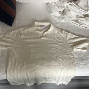 Vit pikétröja i ull från TS Studios XS - Säljer en stilren vit pikétröja från TS Studios i storlek XS. Tröjan är tillverkad i mjuk ull, har klassisk krage och korta ärmar. Perfekt för dig som gillar en clean och enkel look med en touch av preppy stil. Passar nog också en storlek S, den är helt ny, aldrig använd, nypris på omkring 1000kr!