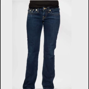 True Religion jeans med broderade fickor - Snygga mörkblå jeans med bootcut passform och coola broderade detaljer på bakfickorna. Klassisk femficksmodell med kontrastsömmar och normal midja. Perfekta för dig som vill ha en tidlös men trendig look. För referens är modellen på bilden 166 cm.