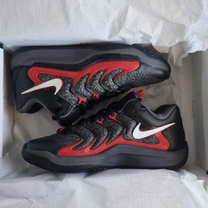 Nike KD17 sneakers svart/röd/grå - Säljer ett par Nike KD sneakers i svart, rött och grått med vit swoosh. Anledningen till att varför jag säljer skorna är för att de är för små och hade svårighet att returnera. De är äkta vara!😊 Ej använda.