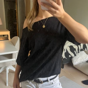 Svart offshoulder topp från Nelly - Säljer en svart offshoulder topp från Nelly i modellen Slouchy Shoulder Tee. Toppen har en lös passform, korta ärmar och är tillverkad i mjuk bomull. Perfekt för en chill och stilren look.😊