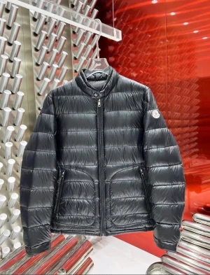 Svart Moncler pufferjacka - Säljer en svart pufferjacka från Moncler med hög krage och diskret logga på ärmen. Jackan har quiltad design, dragkedja framtill och två fickor med dragkedja. Perfekt för kalla dagar och riktigt snygg till streetwear-stilen. Xl passar l