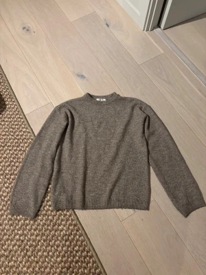 Brun stickad tröja från H&M - Snygg brun stickad tröja från H&M i klassisk modell med rund hals och ribbade muddar vid ärmslut och nederkant. Perfekt för dig som gillar enkel och stilren design. Materialet är mjukt och skönt, passar till många olika looks.