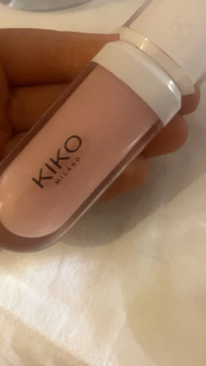 KIKO Lip Volume Tutu Rose - Plumping lip cream från KIKO Milano i färgen 01 Tutu Rose. Kommer i en snygg genomskinlig tub med vit kork. Ger läpparna en mjuk rosa ton och extra volym. Perfekt för dig som vill ha fylligare läppar med en hint av rosa.