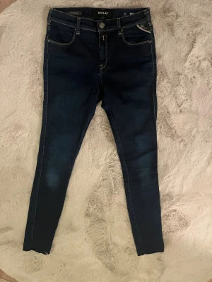 Replay Hyperflex mörkblå skinny jeans - Snygga mörkblå Replay Hyperflex jeans med skinny passform och klassisk femficksdesign. Jeansen har kontrastsömmar, normal midja och är tillverkade i stretchigt jeansmaterial för extra komfort. Perfekta för dig som gillar en tajt siluett och stilren look.