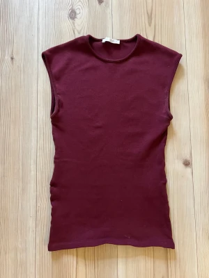 Vinröd ärmlös Bordeaux topp från Zara - S - Säljer en vinröd ärmlös topp från Zara i mjuk bomull. Toppen har rund hals och en slim passform som sitter snyggt mot kroppen. Perfekt att styla med jeans eller kjol för en clean och modern look.