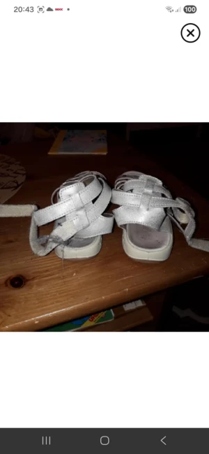 Silvriga sandaler med nitar - Snygga sandaler i silverfärgat syntetmaterial med flera remmar och coola nitar. Skorna har öppen tå och platt sula, samt justerbara remmar som går att knyta runt vristen. Perfekta för sommardagar när du vill ha något bekvämt men ändå stilrent.