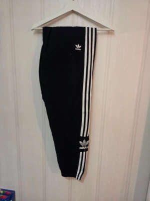 Adidas Originals svarta track pants - Svarta track pants från Adidas Originals med klassiska vita ränder längs sidorna och logga på låret och vaden. Stl S, säljes för 150kr. Djur finns i hemmet!