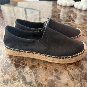 Svarta replay espadrillos  - Snygga svarta espadrillos från replay med grov flätad sula i naturfärgat material och dekorativt guldmärke baktill. Ovandelen är i textil och skon har en klassisk, avslappnad form som passar perfekt till sommaren.