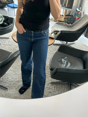 Lågmidjade jeans från Venderby's - Snygga blå jeans från Venderby's i storlek XS. Modellen har raka ben med lite bootcut-vibe, klassisk femficksdesign och kontrastsömmar. Jeansen har normal passform och är tillverkade i jeansmaterial med dragkedja och knapp framtill.