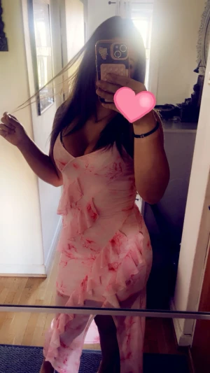 Rosa blommig omlottklänning - Supersöt rosa klänning med blommigt mönster och volangdetaljer. Omlottmodell med v-ringning och slits framtill. Perfekt för sommarens alla tillfällen och ger en romantisk vibe.