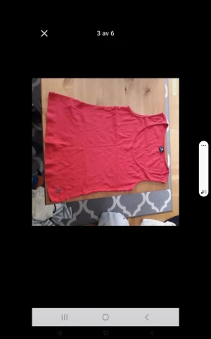 Röd ärmlös linnetopp - Säljer en enkel röd linnetopp med rund halsringning. Toppen är ärmlös och har en avslappnad passform, perfekt för varma dagar. Materialet ser ut att vara mjukt och bekvämt, troligen bomull eller polyester.