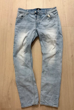 Neuw Ray Straight ljusblå jeans 31/32 - Ljusblå jeans från Neuw i modellen Ray Straight.  Raka ben och knappgylf. Jeansen har en snygg tvätt med ljusa partier och är tillverkade i bomull. Perfekta för dig som gillar en avslappnad och stilren look. Storlek: 31W 32L - Längd: 100cm (se bild),  - midja: 40cm  (se bild) - Inseam: 74cm (se bild).   Tveka inte att höra av dig vid frågor!