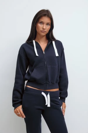 Mörkblå hoodie med dragkedja - Snygg mörkblå hoodie med vit snörning och dragkedja framtill. Tröjan har huva, långa ärmar och en croppad passform som ger en cool och avslappnad look. Perfekt att matcha med mjukisbyxor för en chill stil.