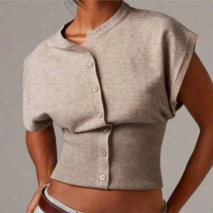 Beige ribbad croppad blus med knappar - Säljer en beige blus med ribbad midja och croppad passform. Toppen har korta ärmar och knappar hela vägen framtill. Enkel och stilren design som är lätt att matcha med jeans eller kjol. Perfekt för dig som gillar neutrala färger och snygga detaljer. Inte mina bilder!💗