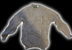 Grå stickad tröja från Donegal Woollen Mill - Säljer en chunky grå stickad tröja från Donegal Woollen Mill. Tröjan har ett klassiskt flätmönster, rund hals och ribbade muddar vid ärmslut och nederkant. Perfekt för kalla dagar och riktigt mysig att bära. Fråga om du vill ha fler bilder eller info!