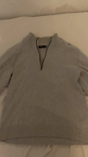 Grå stickad half zip-tröja LMTD - Mysig grå stickad tröja från LMTD i storlek S, med ribbad krage och muddar. Tröjan har en half zip-dragkedja framtill som ger en chill look och är långärmad. Perfekt för dig som gillar enkel och stilren design.kag är villig att sänka pris