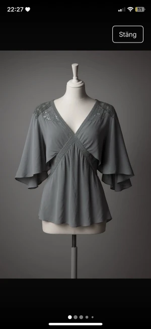 Grå omlottblus med paljettdetaljer - Superfestlig modern blusen med paljetter och kristaller, transparent under armarna 🌸 för en unik touch, dragkedja på ena sidan av midjan ✨, eleganta ärmar och V-ringning som ramar in looken perfekt 💫. Tröjan är bara använd ett fåtal gånger och är i absolut perfekt skick 🌸 – inga tecken på användning alls ✨. 💫