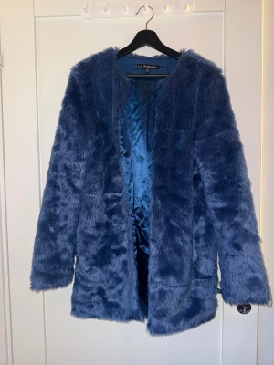 Fusk pälsjacka från For Love & Lemons - Säljer en snygg blå pälsjacka från For Love & Lemons i storlek M. Jackan har lång ärm, är fluffig och har en rak passform. Perfekt för dig som vill sticka ut med en cool och trendig look under kyliga dagar.