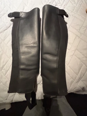 Svarta shortchaps från CRW i äkta skinn, stl S - Ett par klassiska CRW shortchaps i äkta skinn, storlek S. Resårpanel som ger bra passform. Dragkedja och tryckknappar fungerar som de ska.