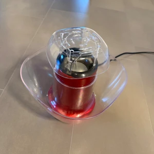 Popcornmaskin - Popcornmaskin i rött med transparent lock och skål. Elektrisk modell, perfekt för hemmabruk. Maskinen ser ut att vara i gott skick utan synliga skador eller slitage. Enkel att använda och rengöra, ger snabb och smidig poppning av popcorn.