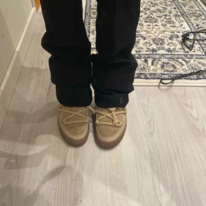 Beige skor från Inuikii - Säljer ett par beige och jätte söta skor från Inuikii med ullfoder och snörning i grovt rep. Skorna har en platt sula, mockadetaljer och bred krage i mjuk päls. Perfekta för kalla dagar och riktigt mysiga att ha på sig. Nypris 3200