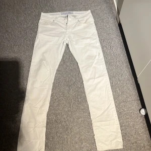 Vita jeans från Jacob Cohen  - Snygga vita jeansbyxor från Jacob Cohen  med klassisk femficksdesign och ikonisk logga på bakfickan. Byxorna har raka ben och silverfärgade knappar och stilren look.