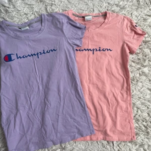 Champion t-shirts - Säljer två snygga Champion t-shirts i storlek M, en i ljuslila och en i ljusrosa. Båda har klassisk Champion-logga tryckt framtill och rund hals. De har även broderad logga på ärmen. Mjukt bomullsmaterial och är inte använda. 