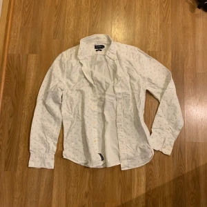 Vit skjorta från East West - Säljer en vit skjorta från East West med små diskreta mönster i hela tyget. Skjortan har klassisk krage, knäppning framtill och långa ärmar med manschett.