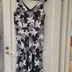 Blommig långklänning från InWear strl 44 - Säljer en svartvit långklänning från InWear med stora blommiga mönster och v-ringad hals och rygg. Klänningen är ärmlös och har en diskret dragkedja i sidan. 100% silk. Klänningen saknar bälte. Storlek 44. Kan hämtas i Vallentuna.