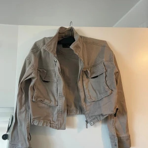 Beige croppad overshirt med fickor - Snygg beige croppad overshirt från Zara med stora bröstfickor, dragkedja och snörning i nederkant. 