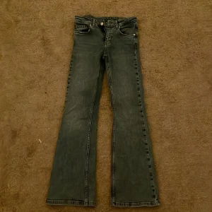 Bootcut jeans, mörkblå - Snygga bootcut jeans i mörkblå tvätt med klassiska fem fickor och orangea sömmar. Jeansen har en rak passform upptill och utsvängda ben, vilket ger en retro vibe. Tillverkade i slitstark denim med dragkedja och knapp framtill. Lite slitna fickor framtill men syns knappt, ser snyggt ut.