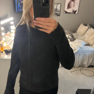 Mörkgrå stickad tröja från Vero Moda - Mysig mörkgrå stickad tröja från Vero Moda. Tröjan har en enkel och klassisk design med rund halsringning och långa ärmar. Perfekt för lager-på-lager och passar till det mesta i garderoben.