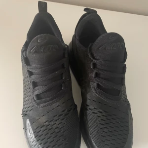 Nike Air Max 270 100% riktiga köpta från Nikes hemsida - Säljer ett par helsvarta Nike Air Max 270 sneakers med snygg mesh-överdel och klassisk Air Max-sula. Skorna har snörning och en sportig vibe, perfekt för dig som gillar streetstyle. Materialet är en mix av syntet och textil för bästa komfort.