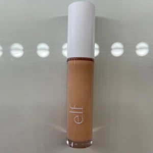 e.l.f. Hydrating Camo Concealer - Hydrating Camo Concealer från e.l.f. i färgen light sand. Kommer i en genomskinlig tub med vit kork och stor applikator för enkel applicering. Perfekt för att täcka mörka ringar och ojämnheter. Krämig formula som återfuktar huden. Använd 3 gånger så mycket produkt kvar.