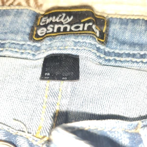 Blå jeans från Emily Esmark - Snygga blå jeans från Emily Esmark med klassisk femficksdesign och gul kontrastsöm. Jeansen har en rak passform och normal midja, tillverkade i slitstarkt denimtyg. Perfekta för dig som gillar en enkel och tidlös stil.