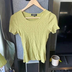 Ljusgrön ribbad topp från K.U.S - Säljer en ljusgrön ribbad topp från K.U.S Stockholm i storlek S. Toppen har rund halsringning och korta ärmar, med en slim passform som sitter snyggt. Materialet är mjukt och stretchigt, perfekt för dig som gillar stilrena och bekväma plagg.